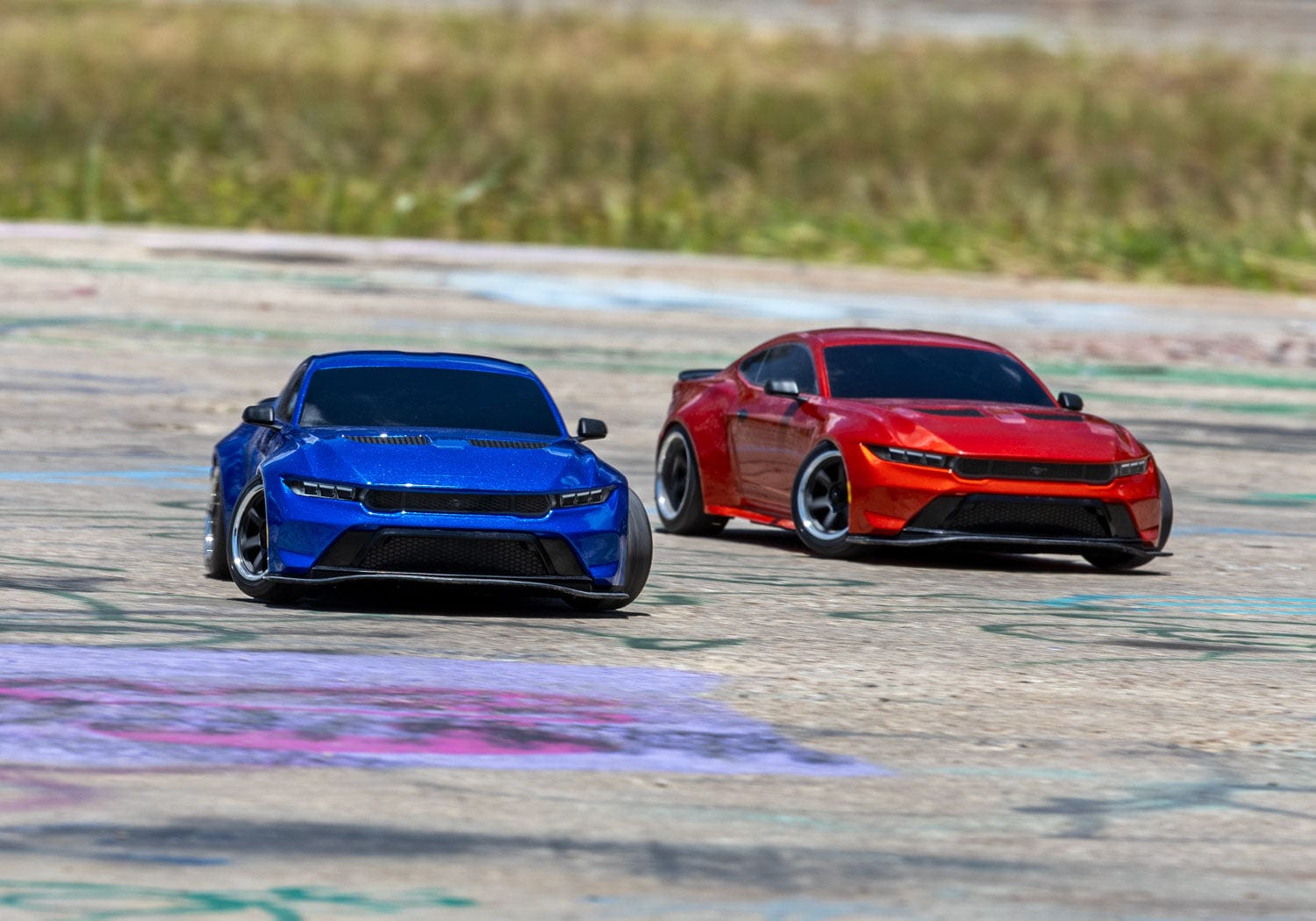 [Action] Traxxas 4-Tec Mustang - mavi ve kırmızı araç açık hava pistinde yarışırken önden