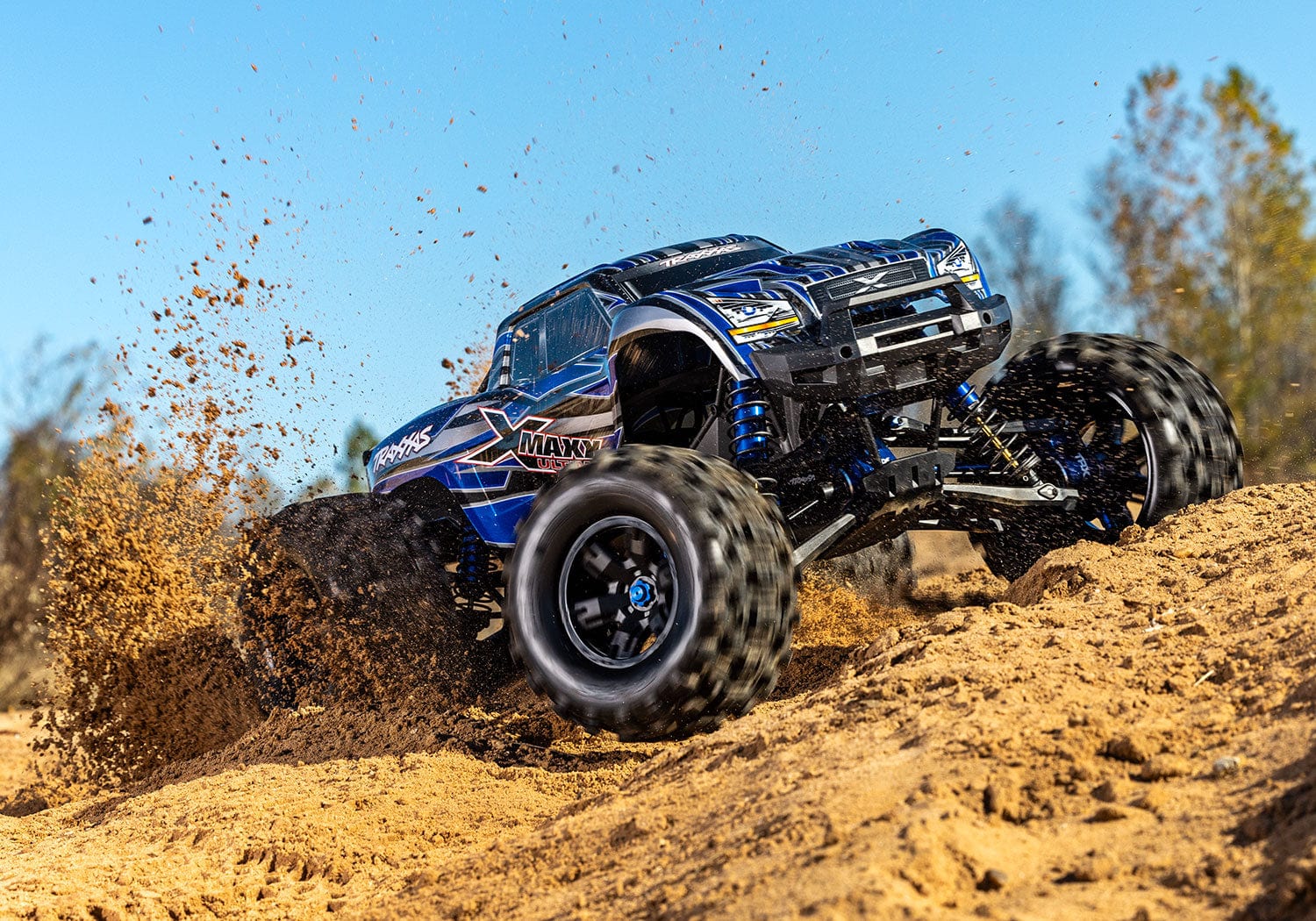 [Action] Traxxas X-Maxx - mavi gövdeli araç kumda toz kaldırarak arazide
