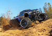 [Action] Traxxas X-Maxx - mavi gövdeli araç kumda toz kaldırarak arazide