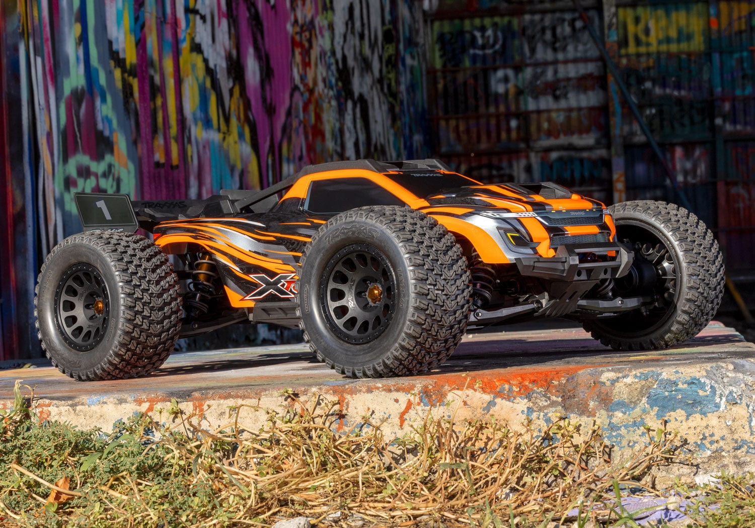 [Action] Traxxas XRT 4WD - turuncu araç grafitili duvar önünde bordür üstünde