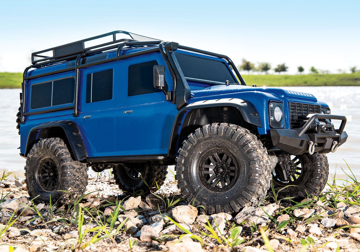 [Action] Traxxas TRX-4 Defender Combo - Mavi Defender göl kenarında çakıllı zeminde sağdan lifestyle çekim
