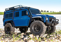 [Action] Traxxas TRX-4 Defender Combo - Mavi Defender göl kenarında çakıllı zeminde sağdan lifestyle çekim