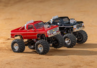 [Action] Traxxas TRX-4MT K10 - Kırmızı K10 ve siyah F-150 monster truck'lar dış mekan kum zeminde yan yana
