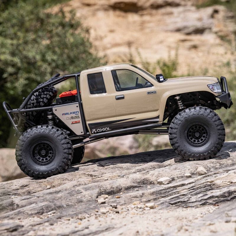 [Action] Axial SCX6 Trail Honcho - kum rengi araç kayalık arazide yandan görünüm
