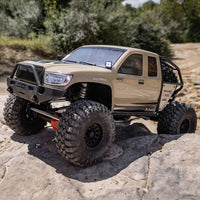 [Action] Axial SCX6 Trail Honcho - kum rengi araç taşlı patikada ön çapraz görünüm