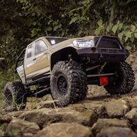 [Action] Axial SCX6 Trail Honcho - kum rengi araç ormanlık kayalık arazide arkadan görünüm