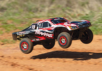 [Action] Traxxas Slayer Pro - kırmızı siyah 15 numara kaplama toprak pistte havada atlayış